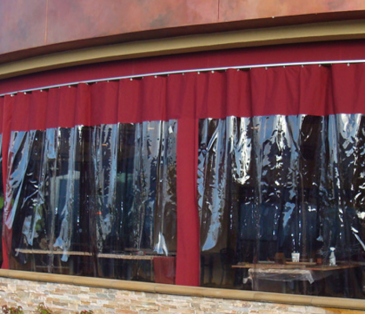 Clear vinyl windows with red fabric borders on a restaurant patio