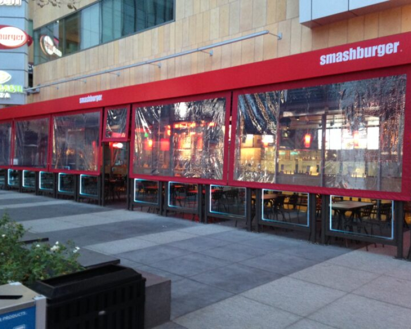 Clear vinyl curtains enclosing the side of a Smashburger restaurant patio